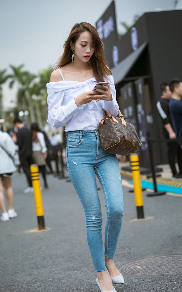 街拍牛仔裤搭配短衬衫美女身材凹凸有致展示时尚靓丽穿搭