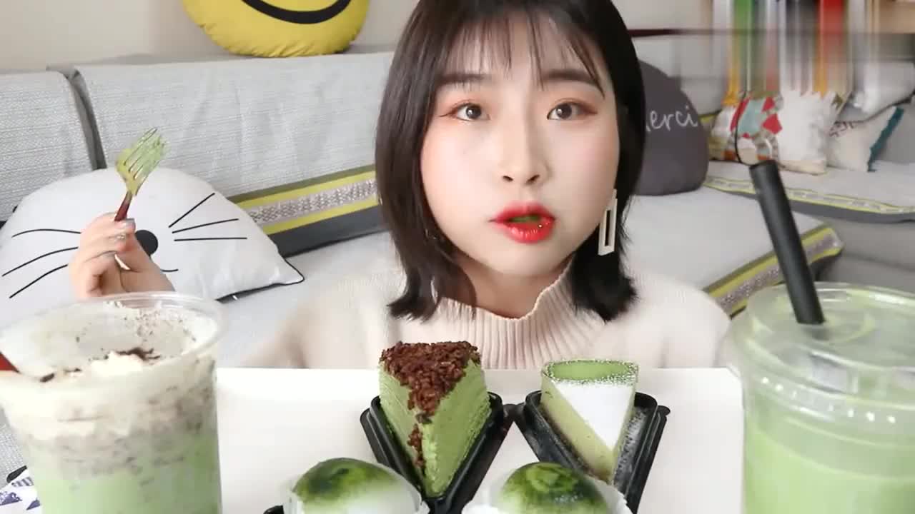 短发美女大口吃抹茶大福，自家的猫在沙发上来回走着玩，太幸福了