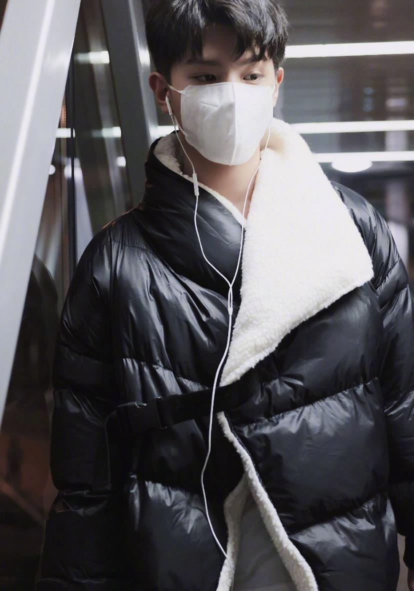 黄明昊机场饭拍图,身着黑色毛绒翻领羽绒服,简约不失时尚
