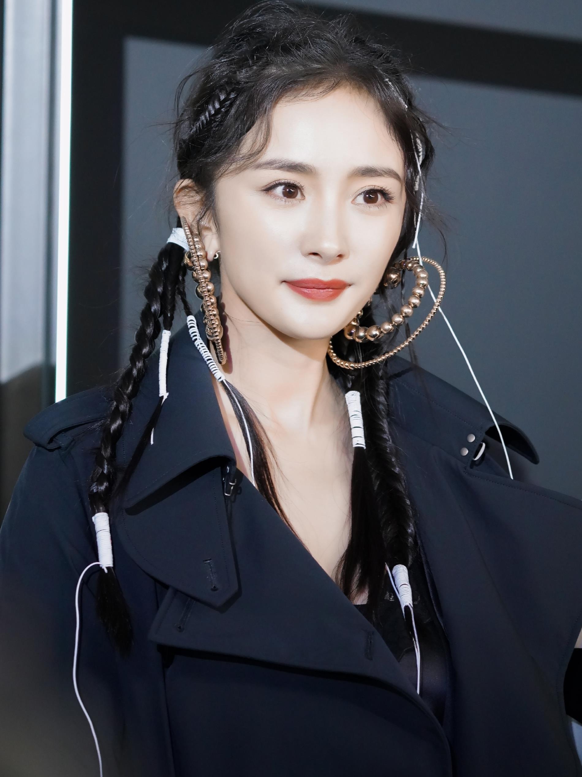 杨幂出席活动,身穿黑色风衣,佩戴超大金珠耳环,前卫时尚