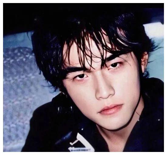 在周杰伦晒出的照片中,20年前的周杰伦留着长长的刘海,穿着黑色的上衣