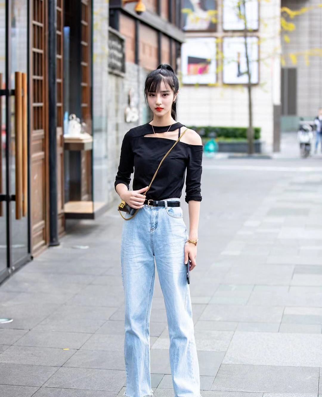 街拍:小姐姐黑色斜肩上衣搭配宽松牛仔裤,身材纤细时尚靓丽