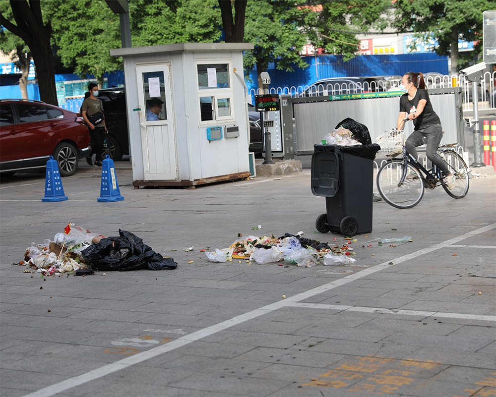 沿街商业街停车场出口垃圾成堆无人管 仅用一垃圾桶遮羞