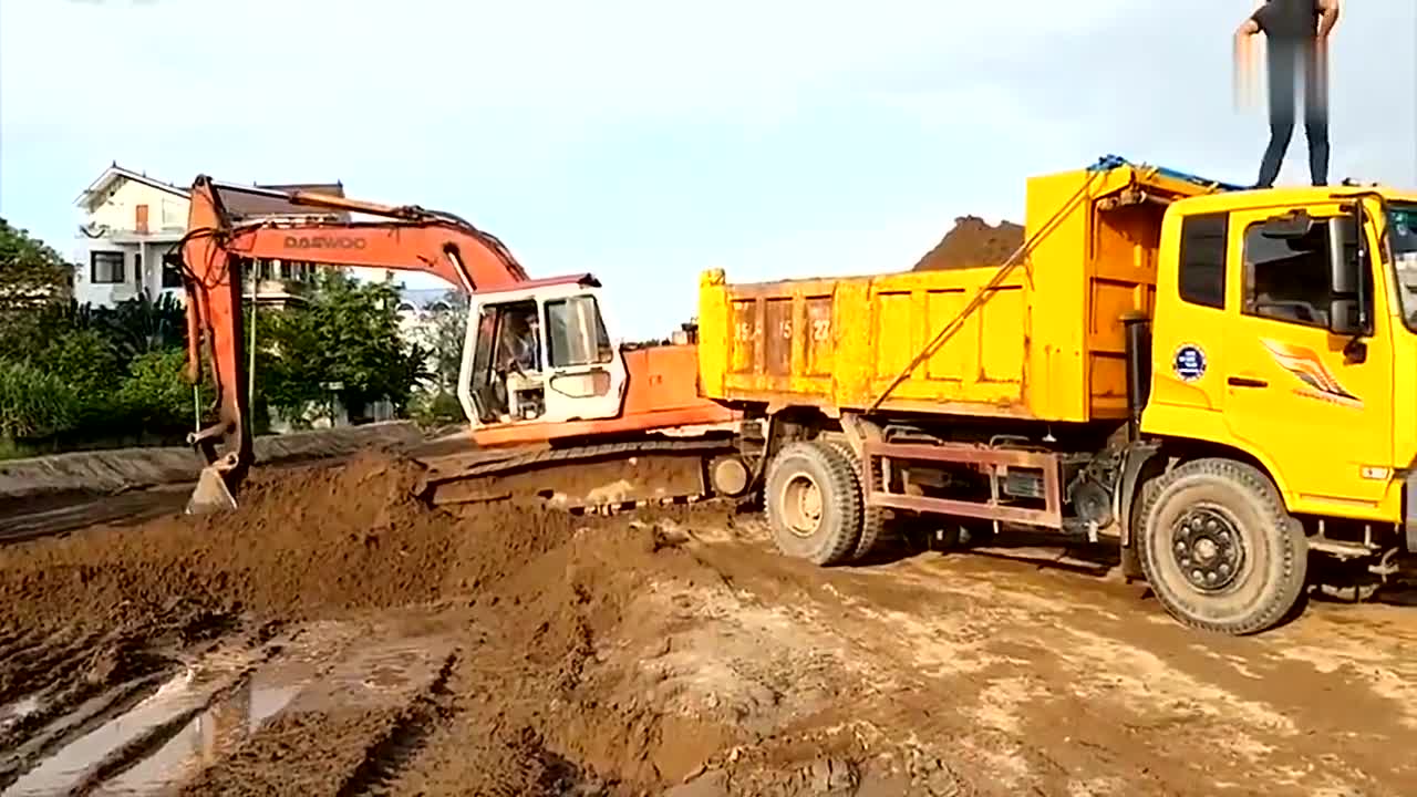 挖掘机正在给卡车装土,卡车司机你站这么高干嘛?