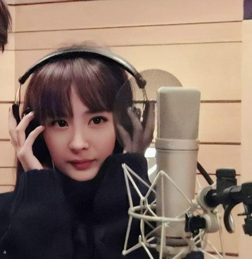 杨幂穿着一件黑色的毛衣,刘海依然是齐刘海,杨幂用双手捂着耳机,虽然