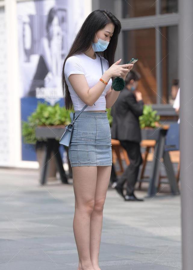 具体来说的话,这位小姐姐所选择的牛仔短裙选用了修身的剪裁,考虑到