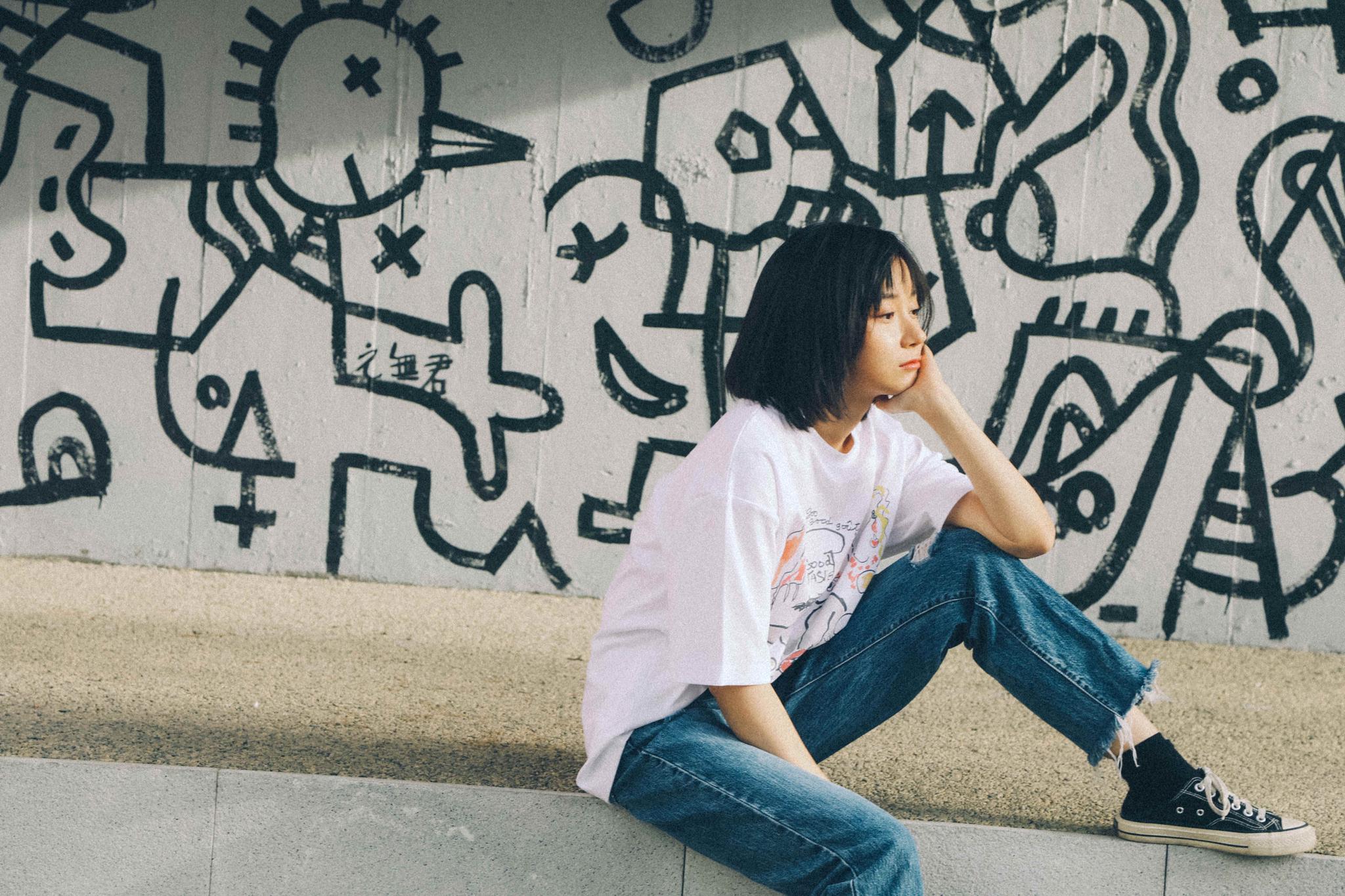涂鸦墙作为背景,卜冠今安静地面对镜头,时而露出甜笑