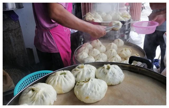 门口的台子上摞满了笼屉,每个笼屉里都是满满的包子,客人拿着塑料袋