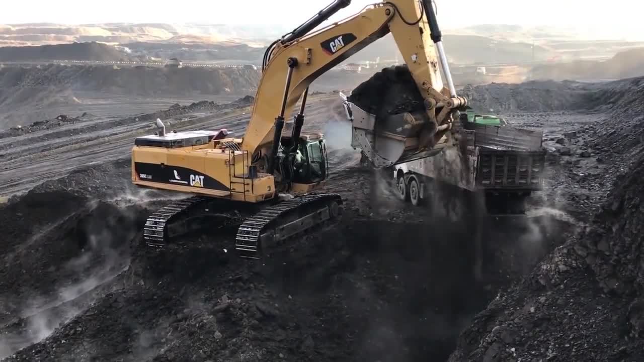 卡特大型挖掘机在露天煤矿作业一分多钟装满重型自卸车