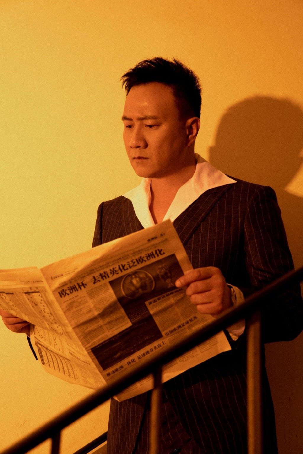 胡军身穿白色翻领衬衫,搭海蓝条纹西装和深咖翻领条纹衬衫