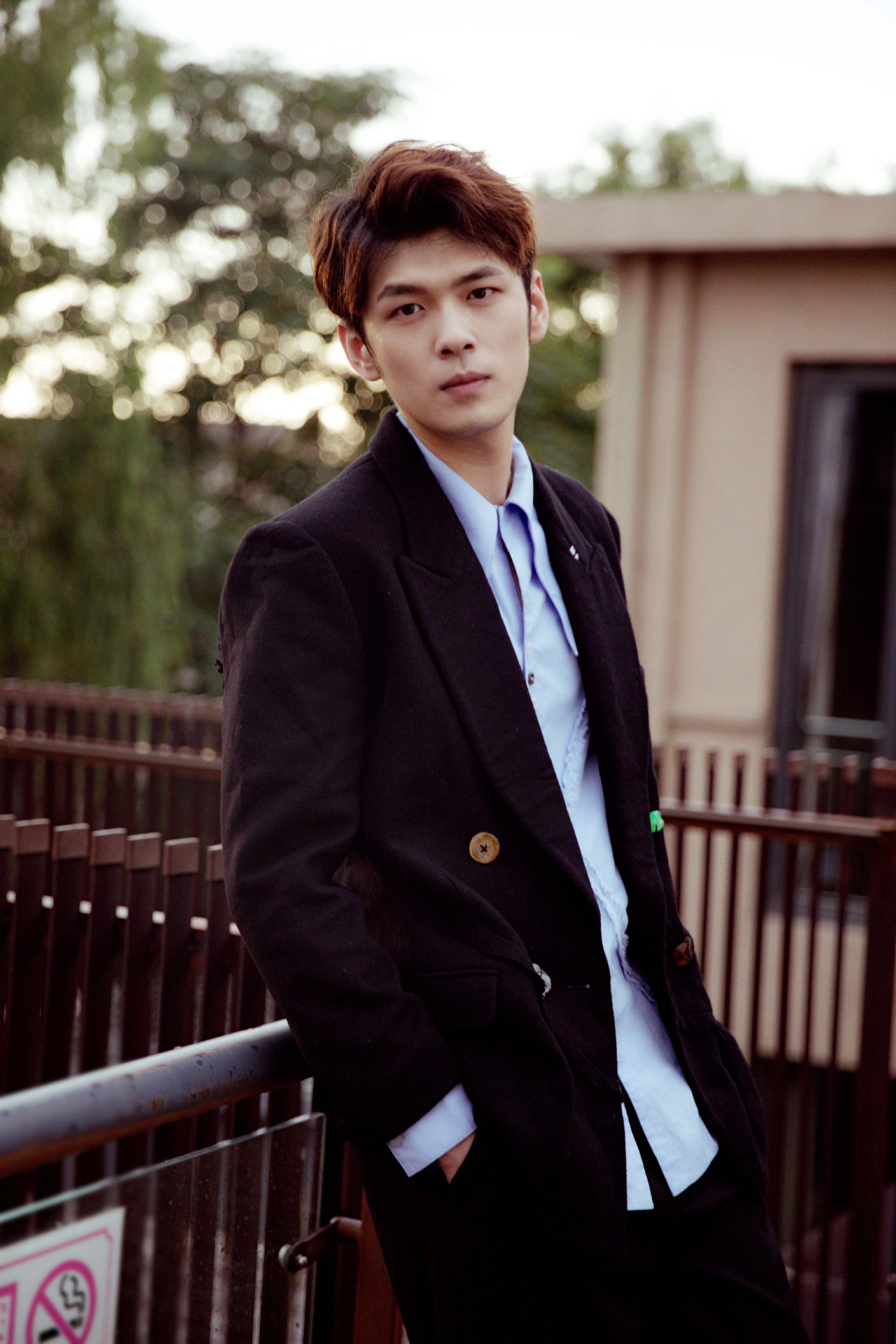 照片中,盛英豪置身于废旧的楼宇,身着天蓝色衬衫搭配黑色花扣西装,或