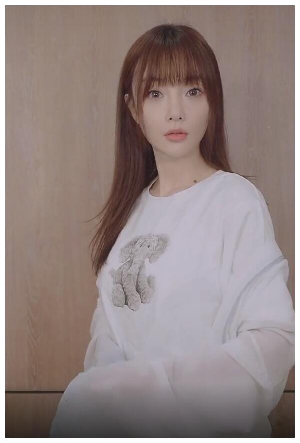 视频一开头,李小璐披散长发留着齐刘海,化着精致妆容,穿着白色t恤配