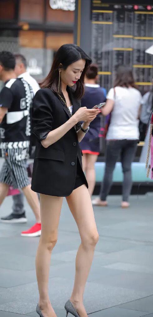 图片中的街拍美女穿着一件小香风的黑色西装,职场范儿十足,属于都市