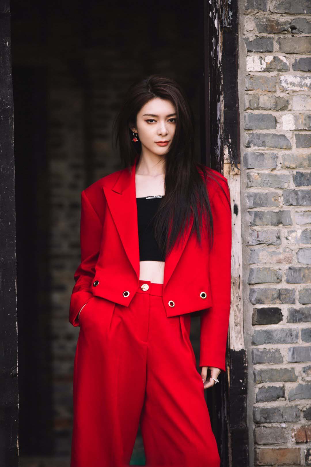 傅菁身着红色西装,正红色与青砖的配色尽显高级质感__财经头条