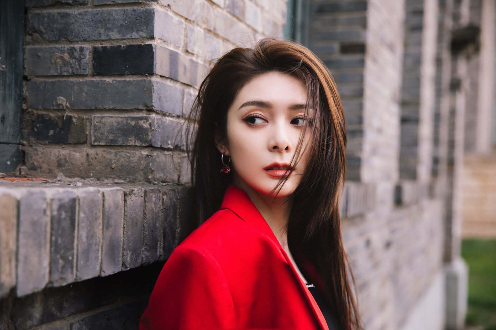 傅菁身着红色西装,正红色与青砖的配色尽显高级质感__财经头条