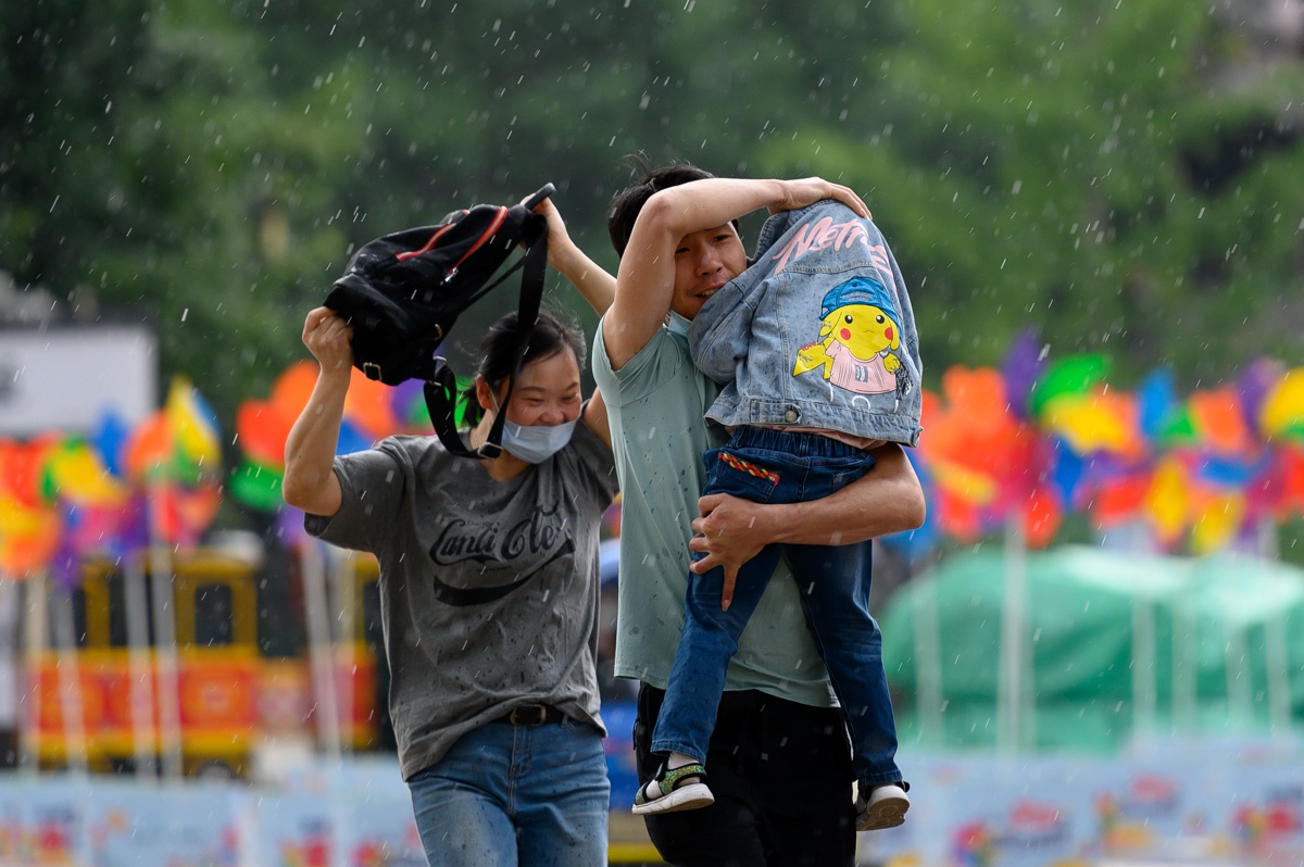 六一儿童节突降大雨,外出游玩的家长为孩子遮风挡雨