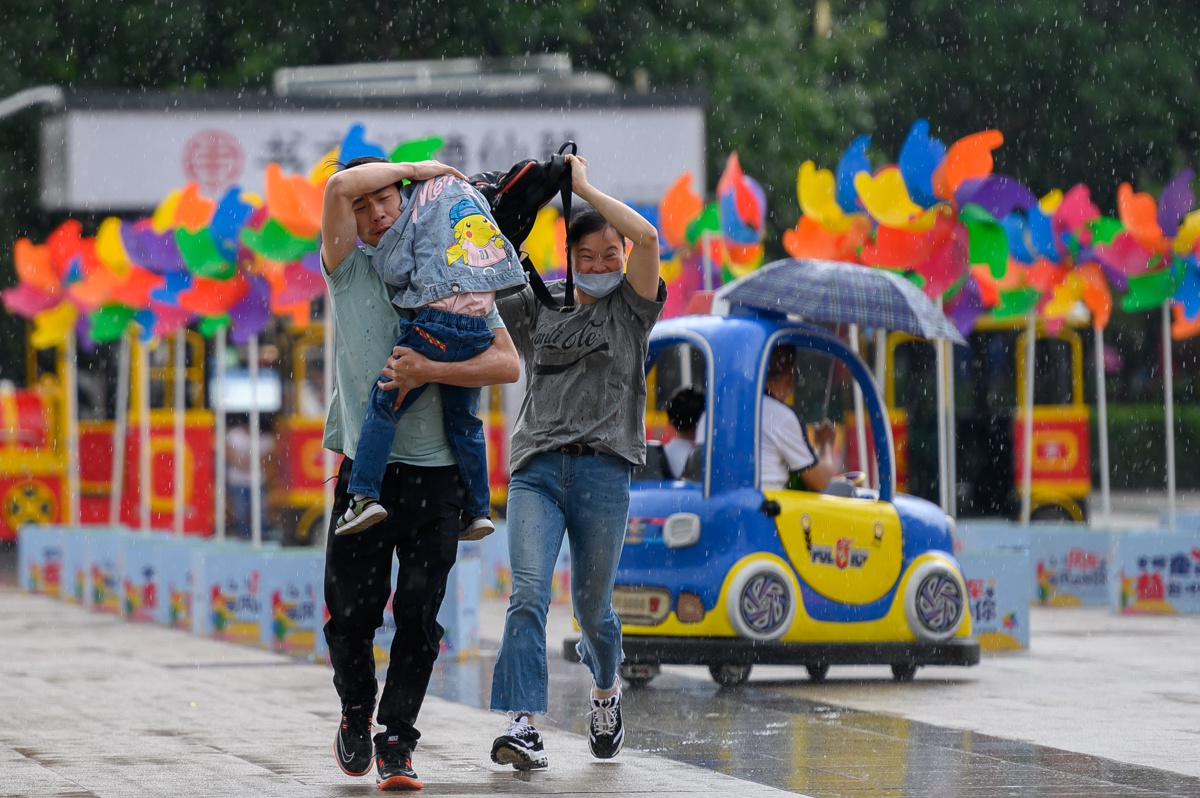 六一儿童节突降大雨,外出游玩的家长为孩子遮风挡雨