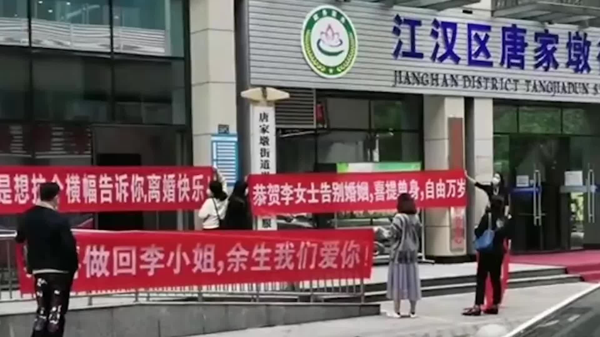 女子离婚好友在婚姻登记处外拉横幅庆祝 现场双方互道恭喜后离开