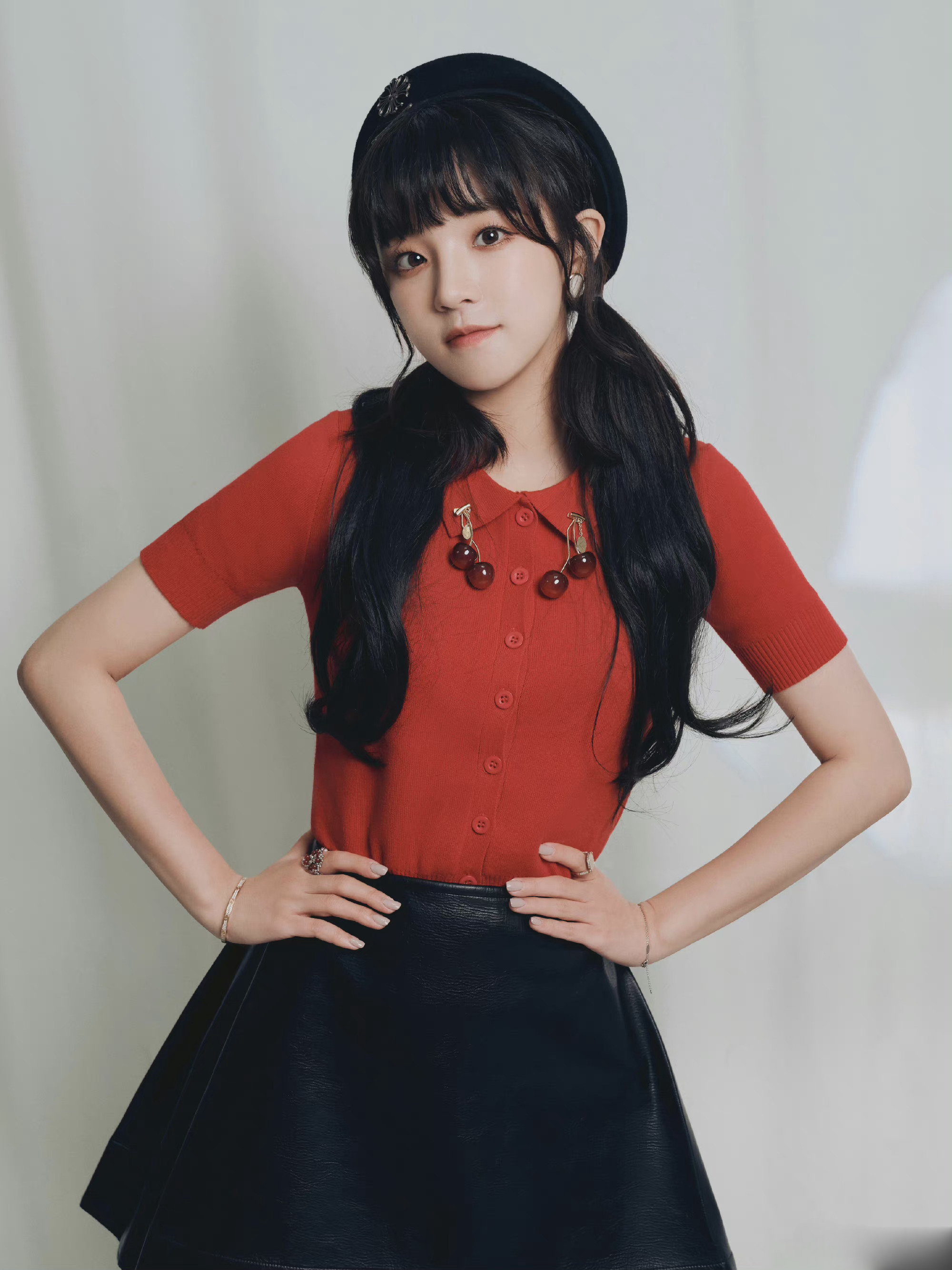 宋雨琦身着橙红色针织上衣和黑色皮裙,搭配黑色皮鞋