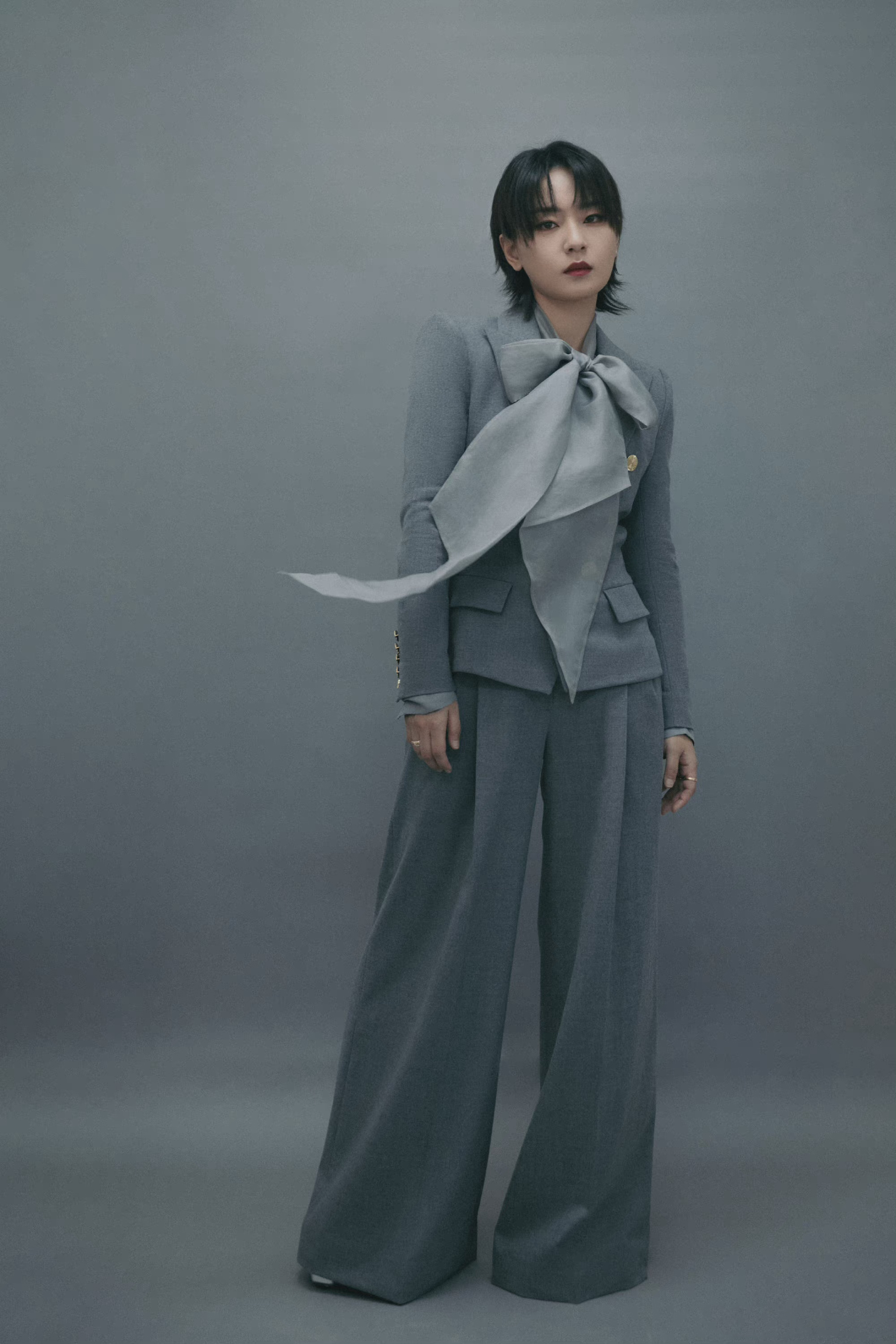 周笔畅身穿质感灰色西服套装,蝴蝶结飘带点缀,尽显利落洒脱