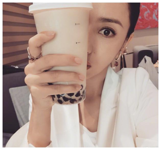 戴着首饰妆容精致,奶茶遮住了大半张脸,显得人愈发小巧