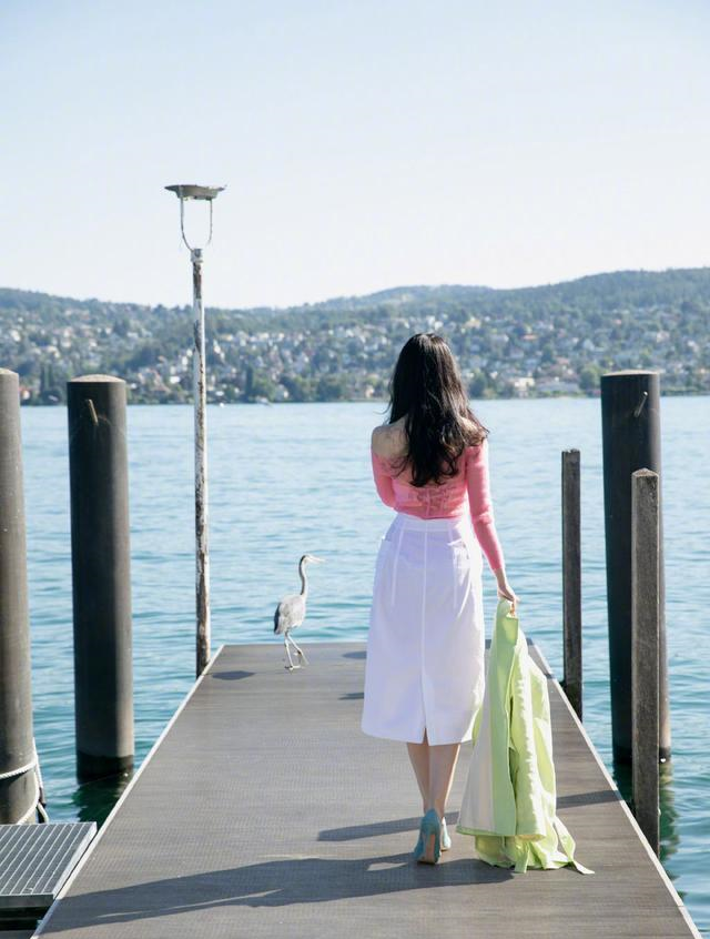 穿着一双绿色的高跟鞋,颜色搭配特别的夏日,一头长发披肩,这个背影也