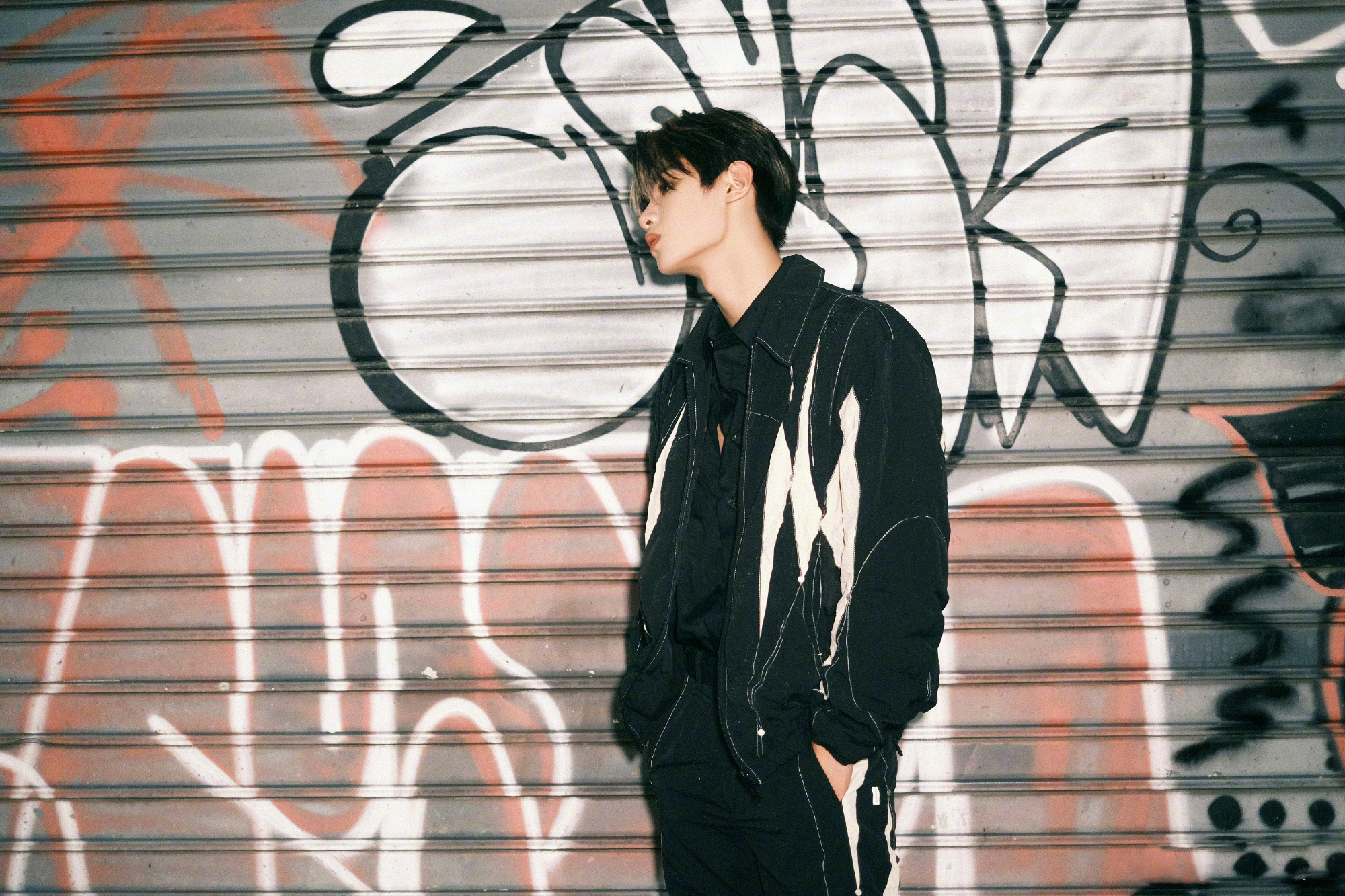 黄明昊一身黑白工装风套装出镜雨夜街头光影交织定格回眸