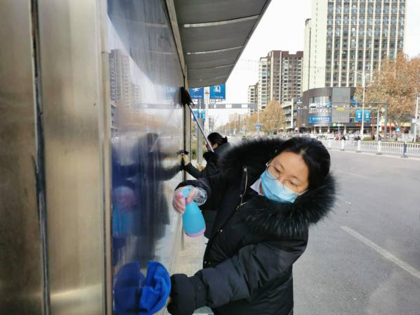 水盆,抹布等清洁工具来到了马路对面的公交站牌进行打扫和清理工作
