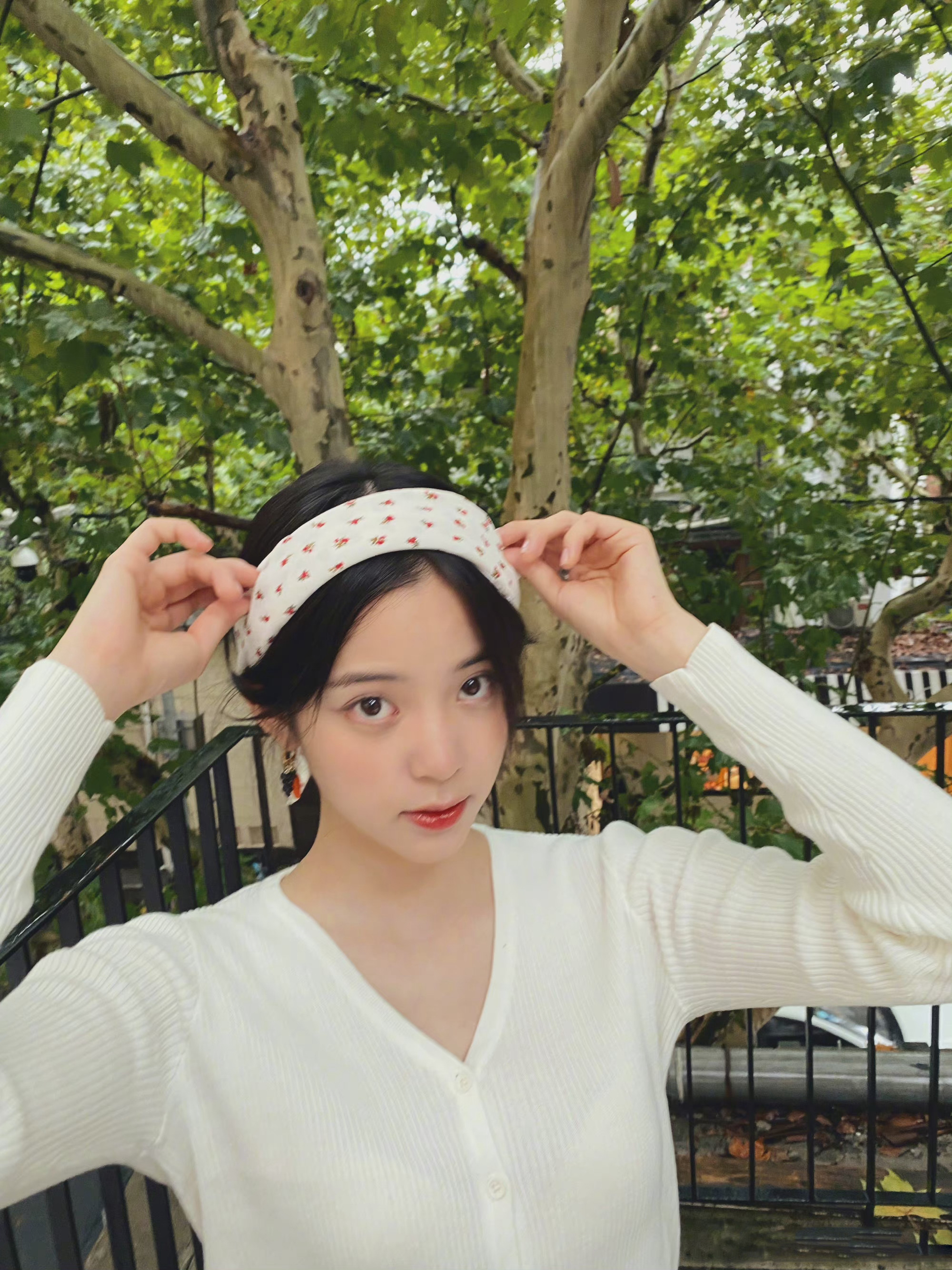 欧阳娜娜身穿白色针织上衣,搭配黑色百褶裙,印花发带俏皮可爱
