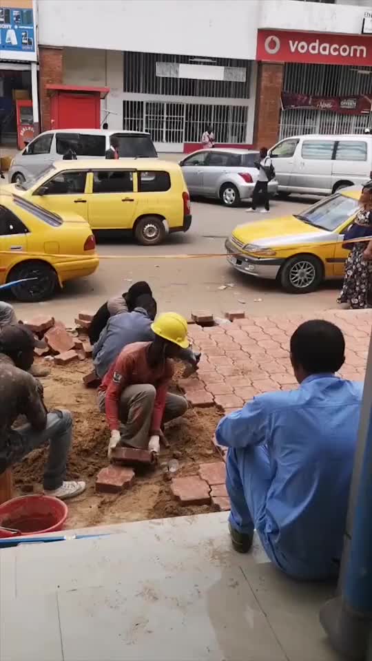 非洲工人在铺砖一半人干活另一半人监工