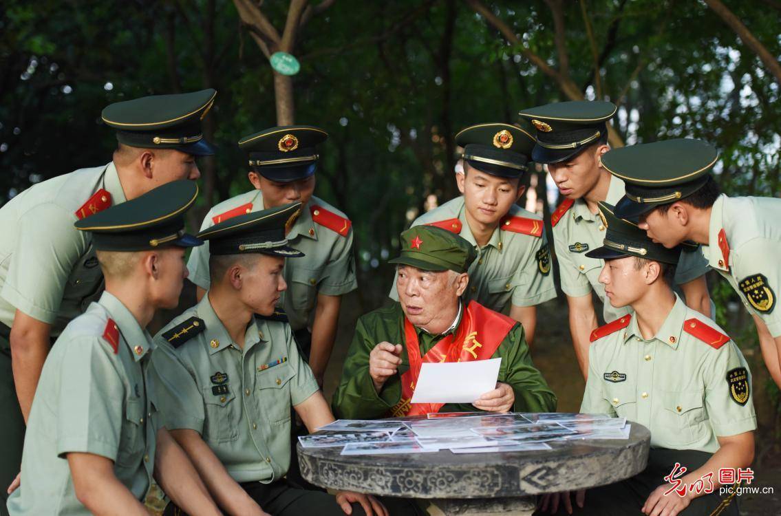 2021年7月20日,"红色故事讲解员"李明友老兵在向官兵介绍老照片背后的