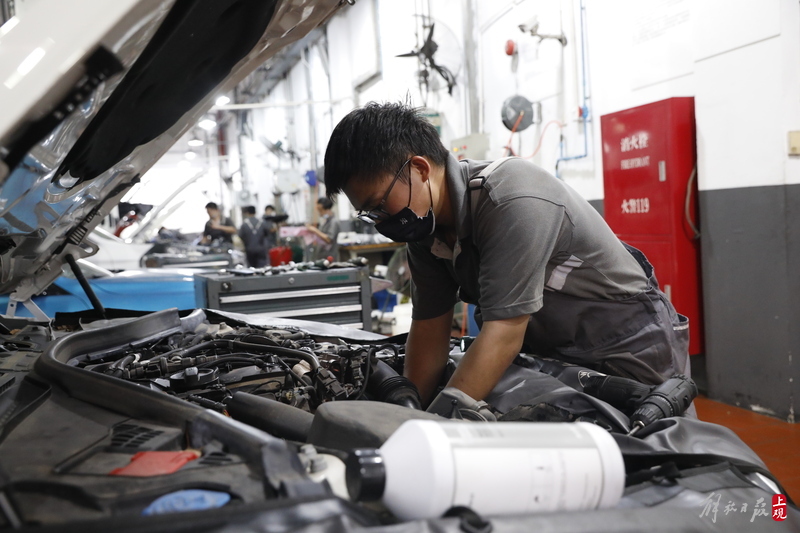 上海市宝山区长江西路一家汽车4s店维修车间内,维修工人们在热浪和