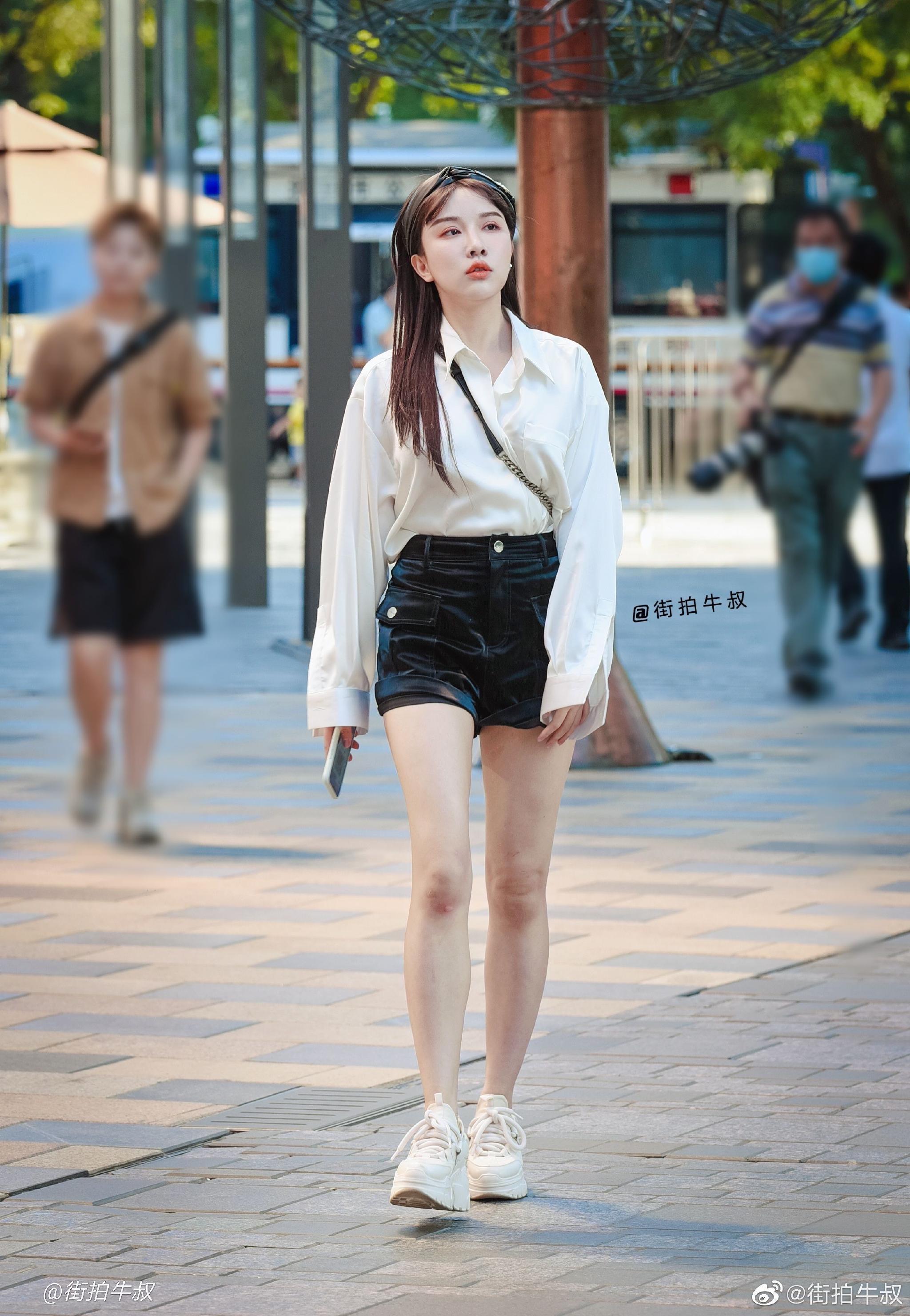 美女穿着漂亮的白衬衫黑色热裤出街