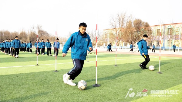 2021年12月24日,托克逊县夏乡中心学校足球班的学生在操场上练球.