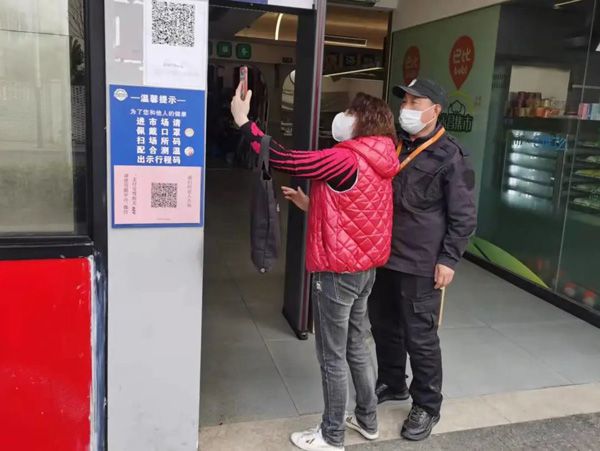 市场工作人员指导居民扫场所码"主动扫码做示范,助力