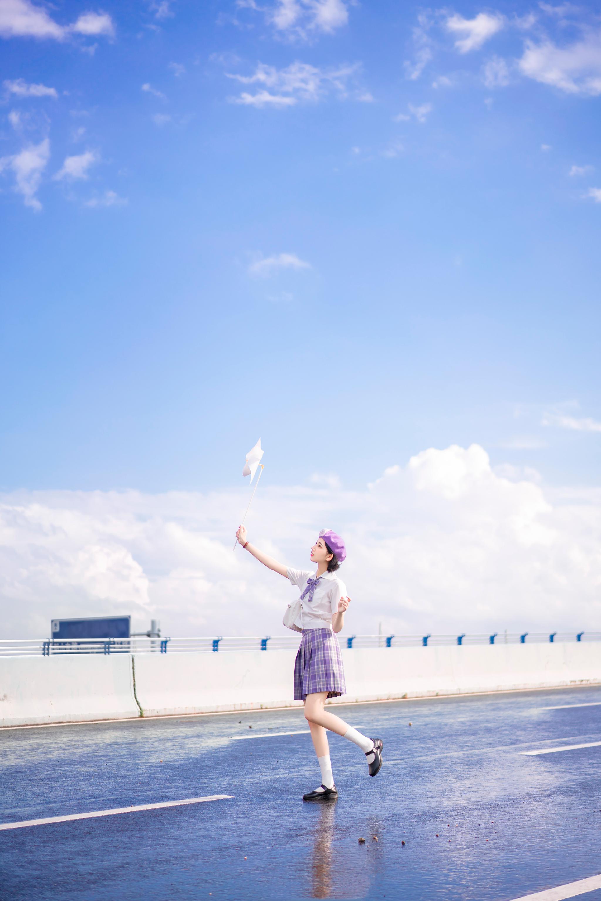 镜头里小姐姐身处下过雨后的公路旁,蓝色的天空背景下少女倩影明亮,一
