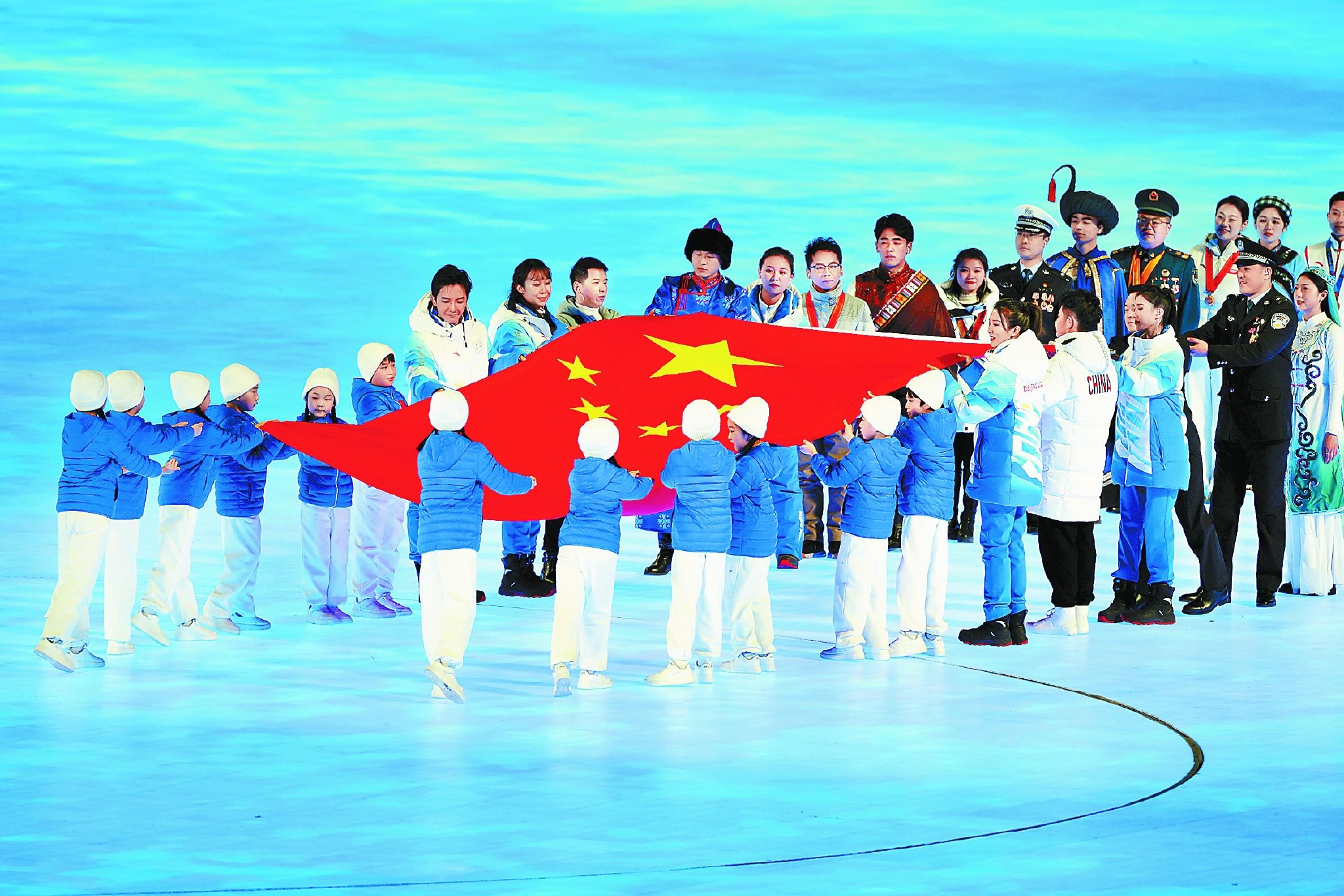 国旗在12名少年儿童手中展开,传递给全国各行各业和56个民族的代表.
