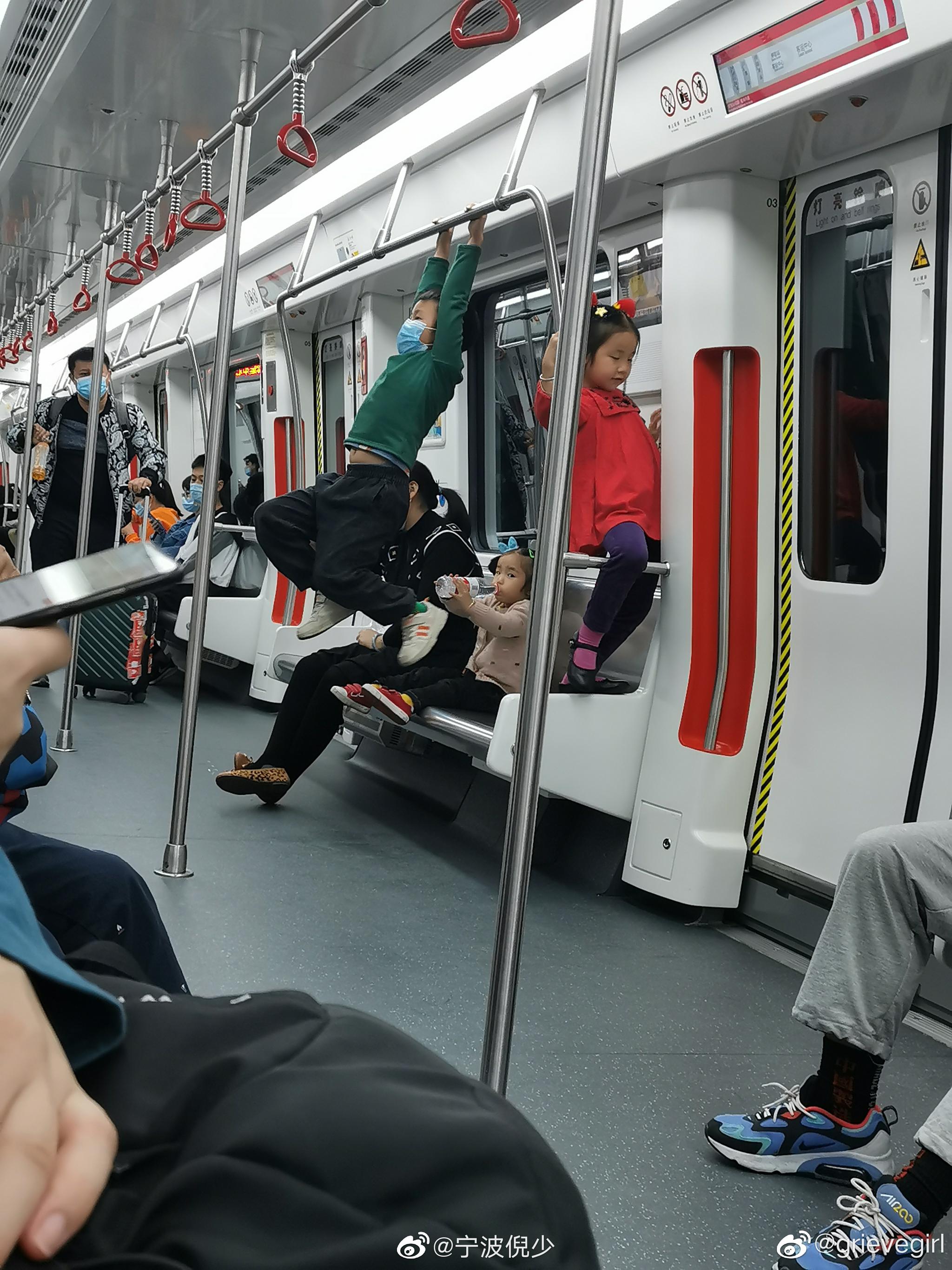 小孩子在地铁上扶手当单杠玩