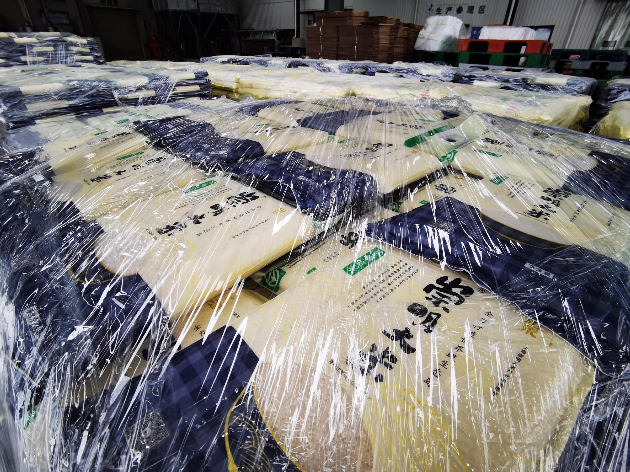 全自动加工包装流水线马力全开,工人们正在忙着整理包装好的大米,准备