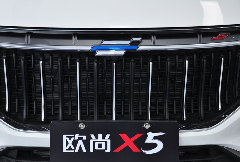 以简洁著称的长安欧尚车标,与中网里的横条融在一起,左上角还有个红色