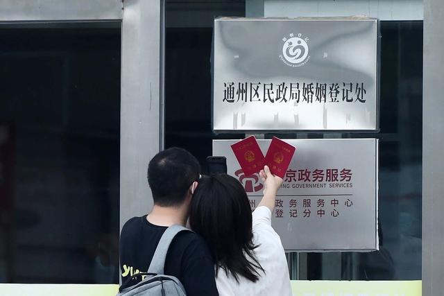 新人在通州区民政局门口高举结婚证拍照留念.