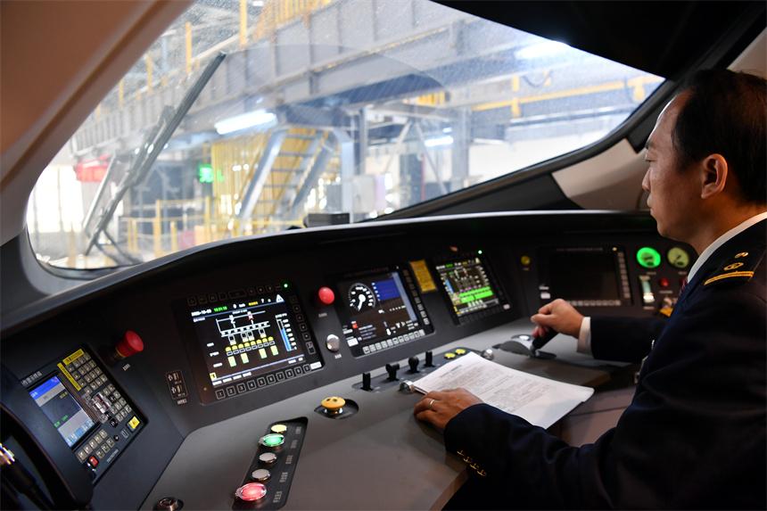 复兴号智能动车组司机正在驾驶室内操控设备.