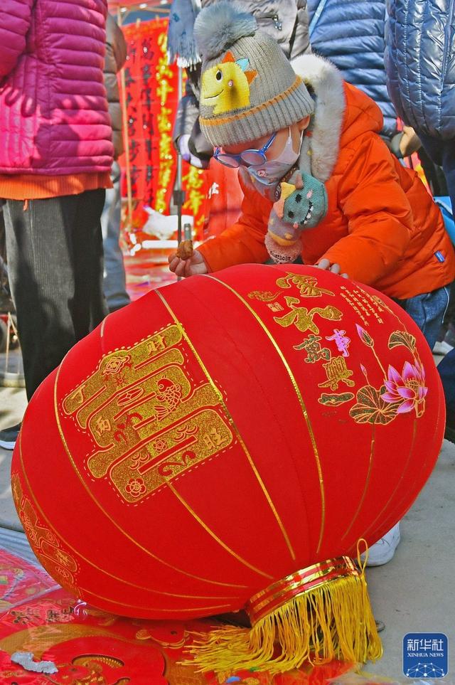 1月18日,小朋友在山东省烟台市福山大集选购灯笼.