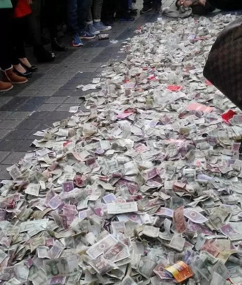 乞丐在地上放了好多乞讨来的钱,不说话路人纷纷扔钱图吉利
