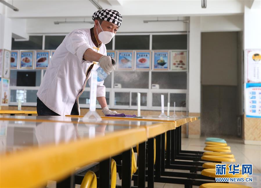 3月21日,银川市第二中学食堂工作人员对食堂餐桌进行消毒.