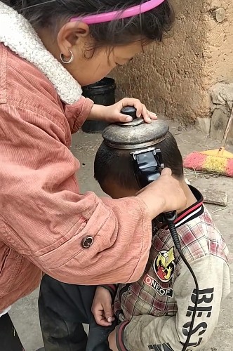 真巧,用只旧壶盖,姐姐就给弟弟理头发,可背后家事使人眼睛发酸