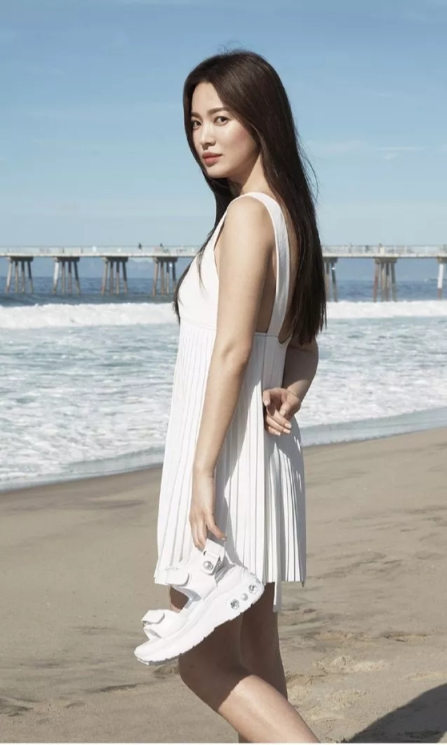 宋慧乔全新美照曝光,吊带露脐装显丰满,穿白裙拎着鞋在沙滩漫步