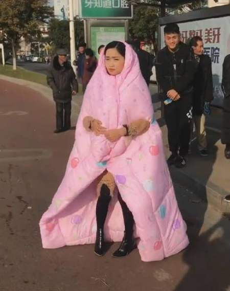 女子闹市区裹着棉被等公交得知原因后众人都懵了