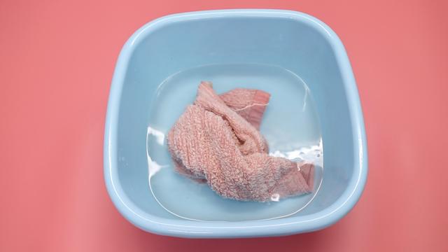 然后把水搅拌均匀,我们把毛巾放入水里,让毛巾全部浸湿,浸湿以后把