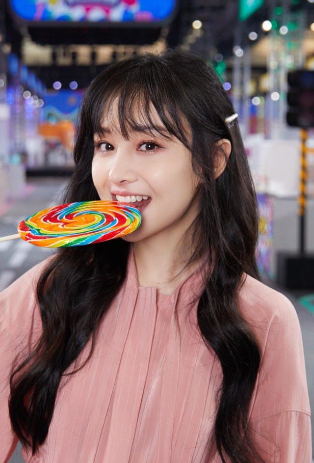 郑爽粉色连衣裙配大波浪,手持棒棒糖,画风十分甜美俏皮